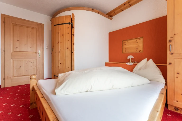 Einzelzimmer mit warmer Farbgestaltung und traditionellem Holzbett im Sagritzer Wirt, Familienbetrieb im Mölltal