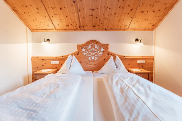 Traditionelles Doppelzimmer mit zwei Einzelbetten und geschnitztem Holzkopfteil im Sagritzer Wirt, Urlaub im Nationalpark Hohe Tauern