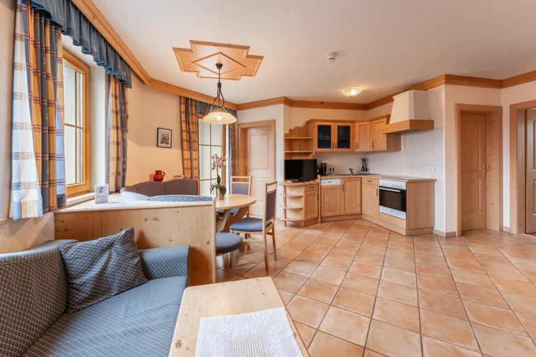 Geräumiges Wohnzimmer mit Küche und traditioneller Holzeinrichtung in der Ferienwohnung beim Sagritzer Wirt im Mölltal