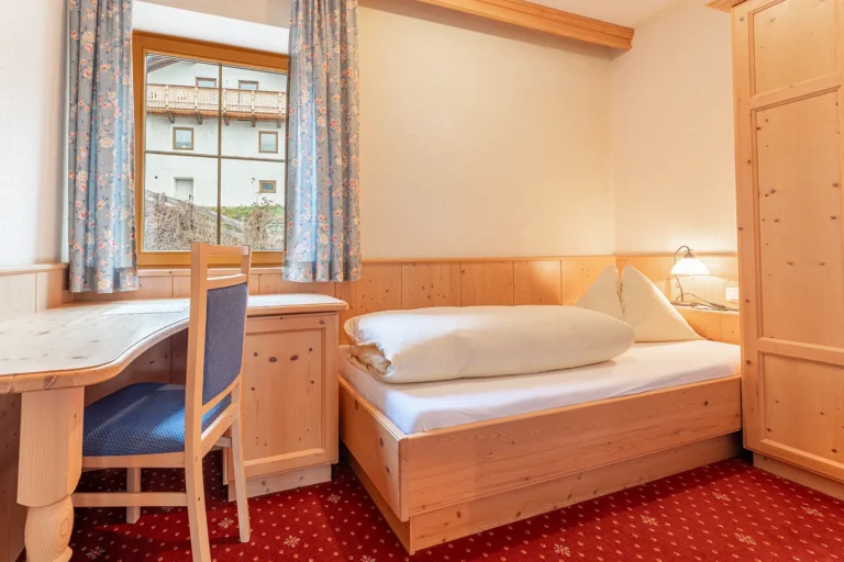 Einzelzimmer mit Schreibtisch, Zirbenbett und Fensterblick in der Ferienwohnung Turm, Sagritzer Wirt Großkirchheim